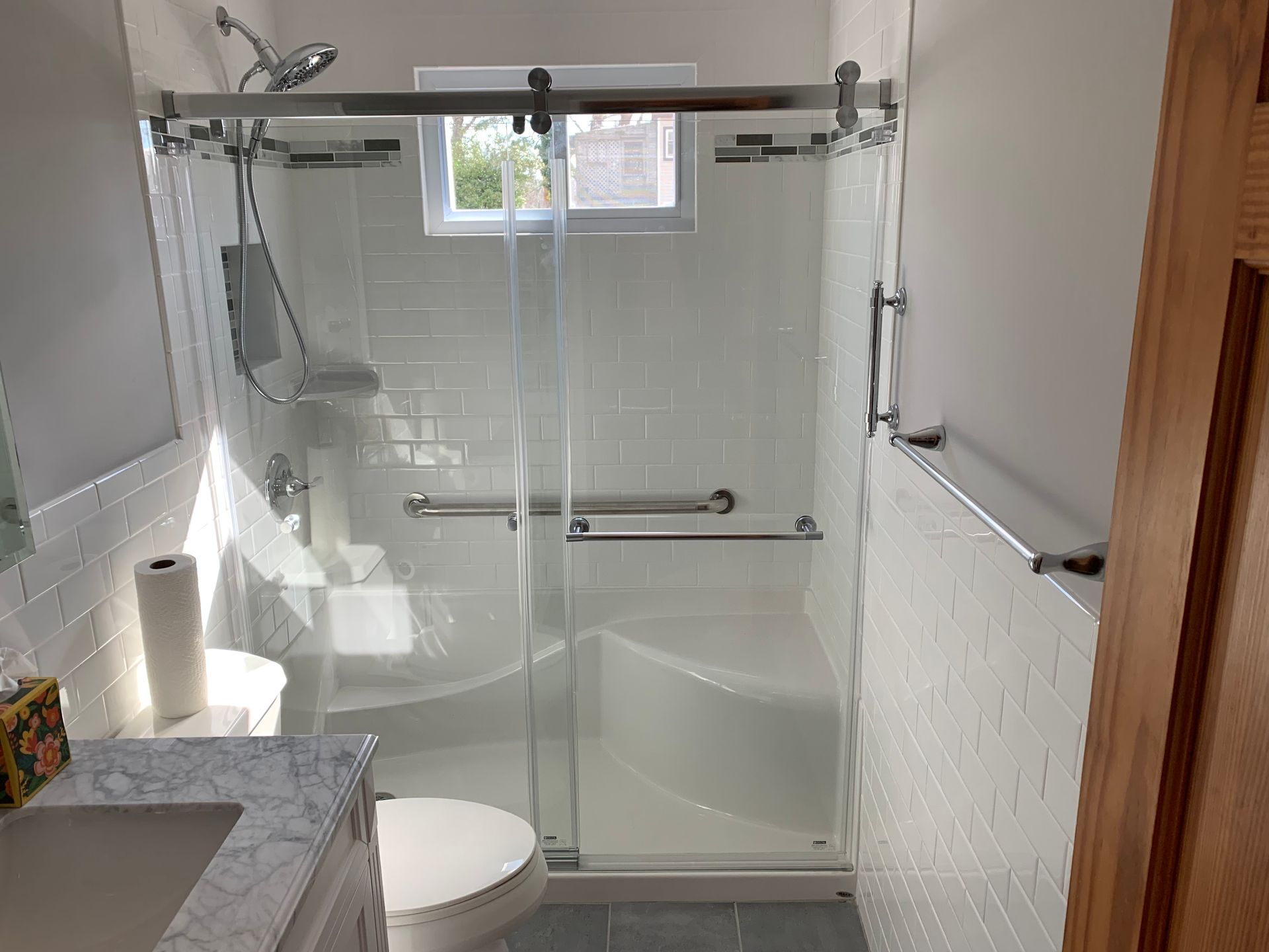 Accessible bathroom with a white tile shower, bench, and grab bars.