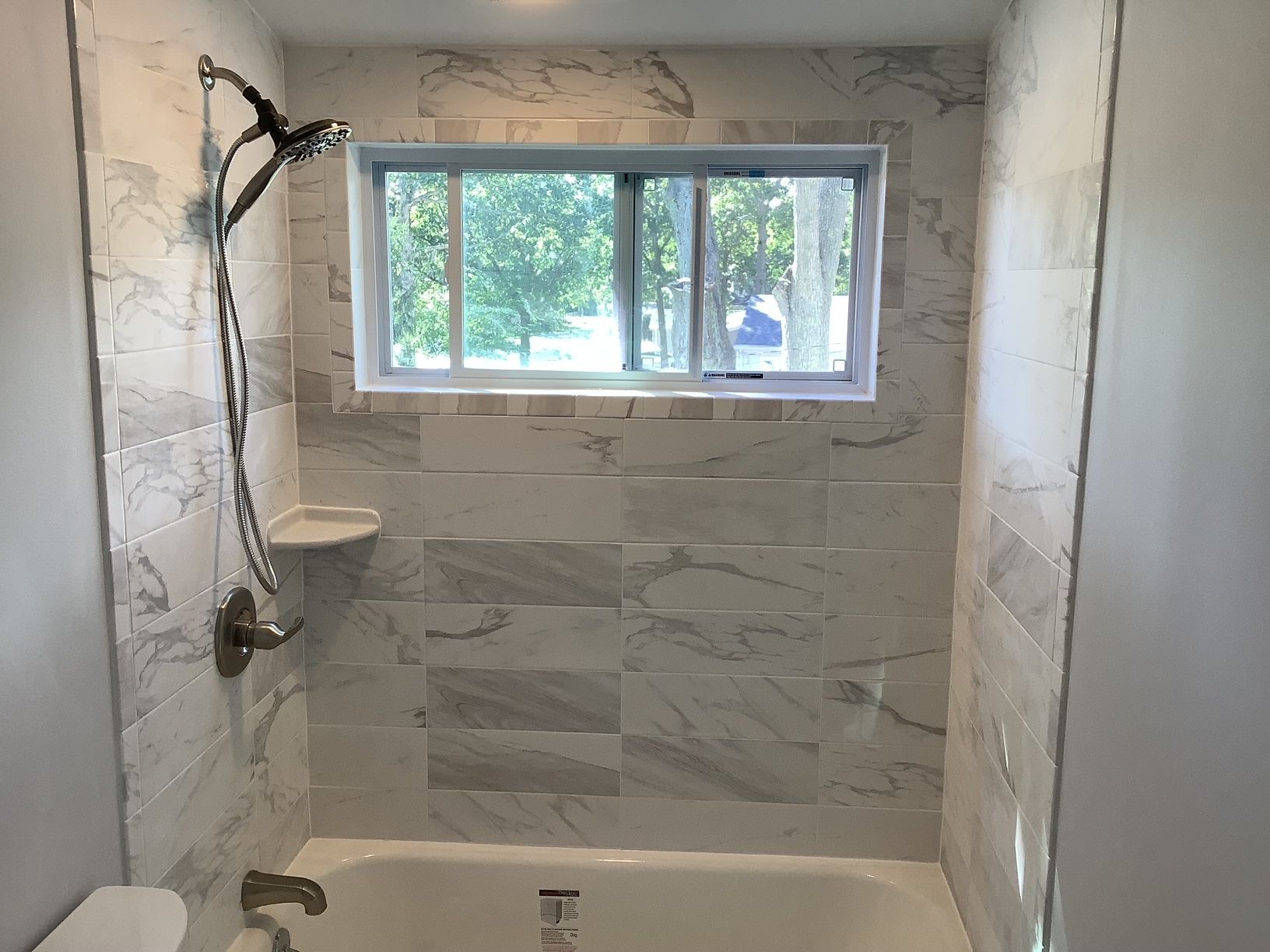 A bathroom with a tub, shower, and window