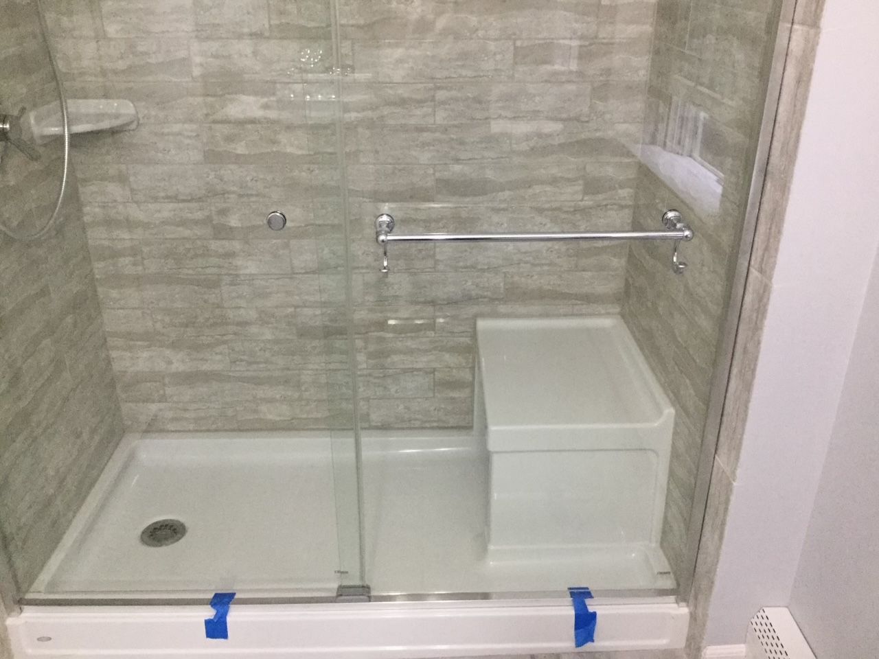 A bathroom with a walk in shower and a bench
