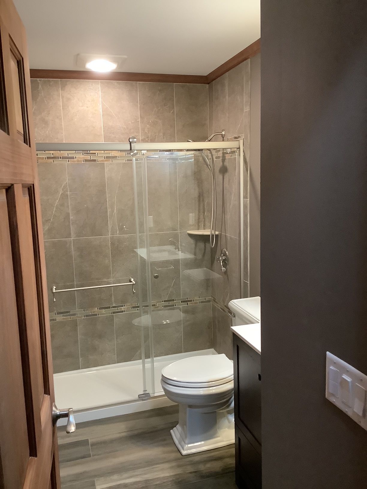 A bathroom with a toilet, sink, shower, and sliding glass doors