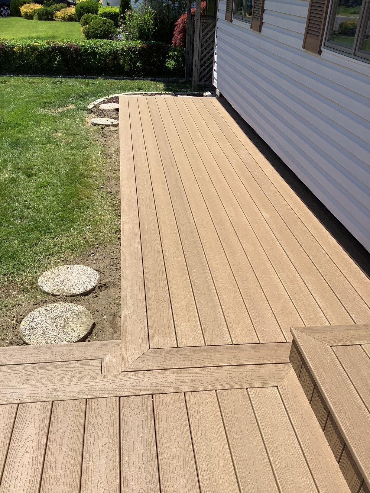 A wooden deck with stairs leading up to it next to a house