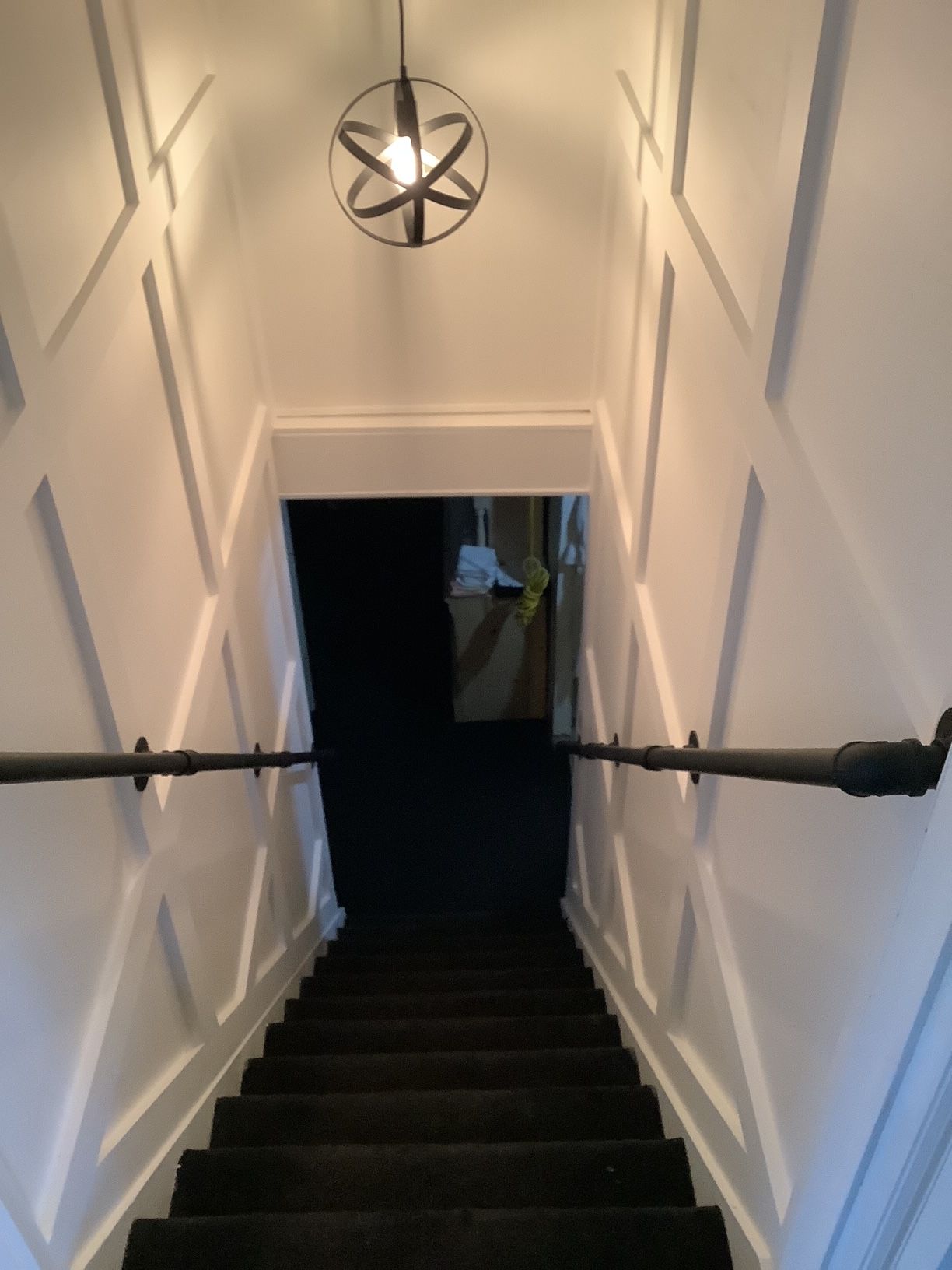 A set of stairs leading up to a room with a light hanging from the ceiling