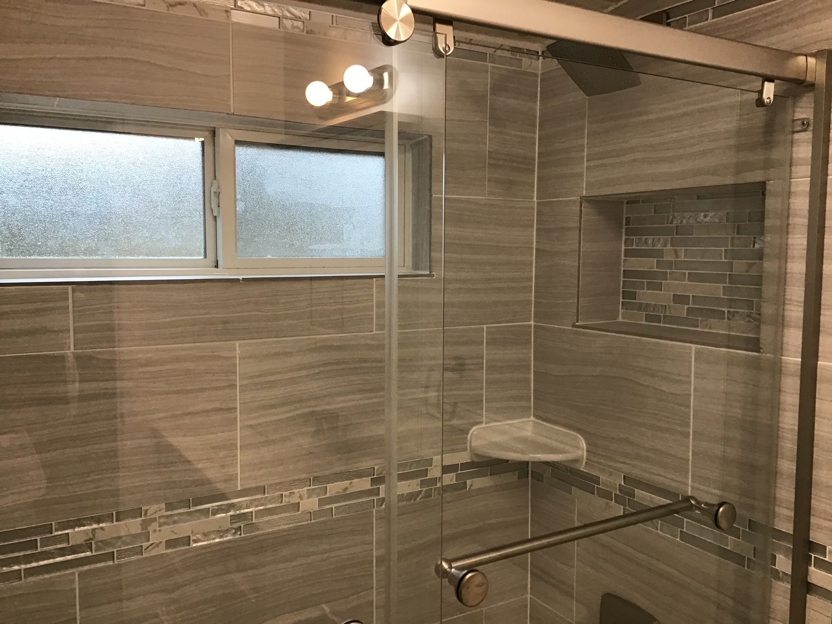 A bathroom with a sliding glass shower door and a window