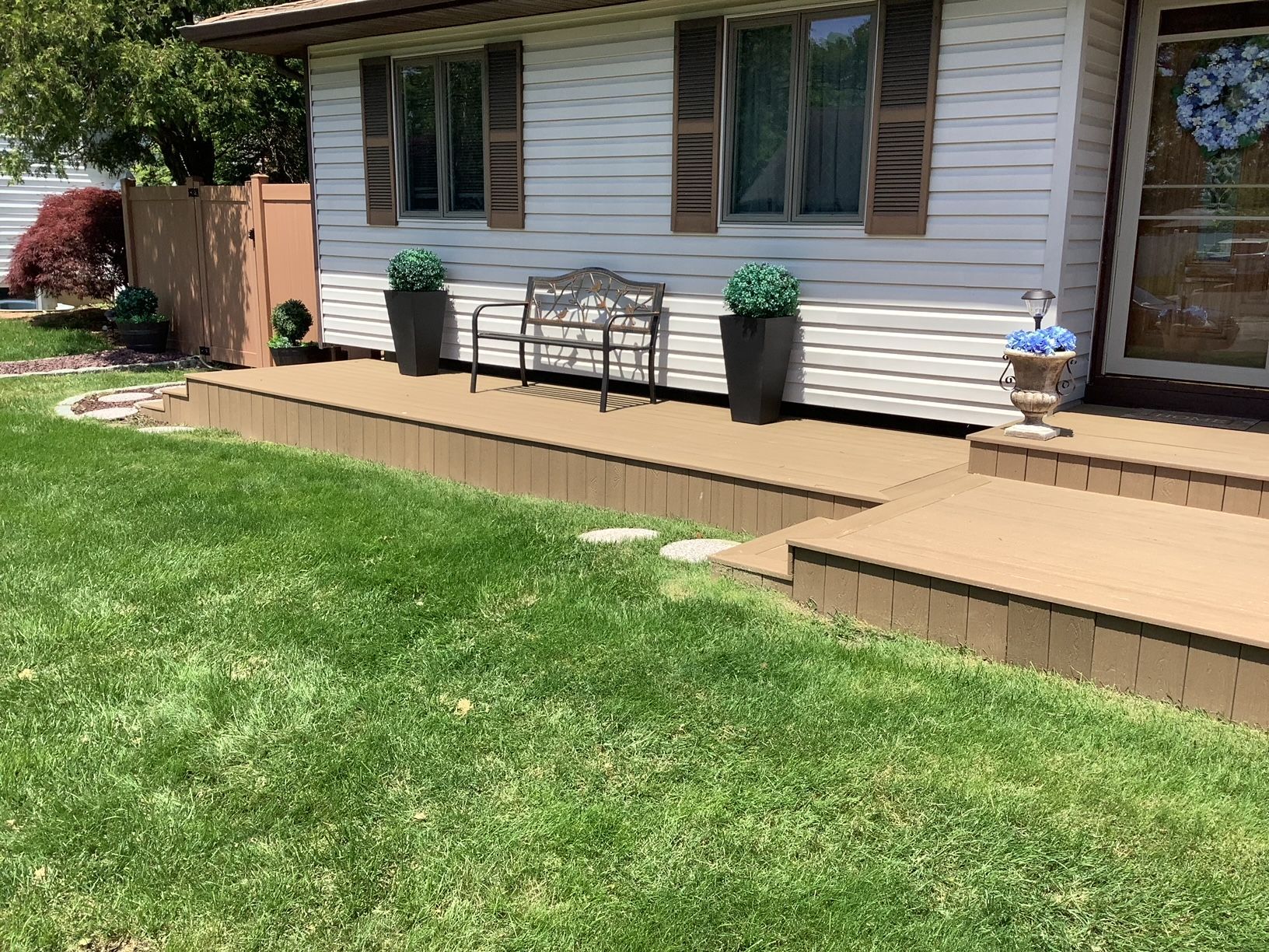 A white house with a wooden deck and a bench in front of it