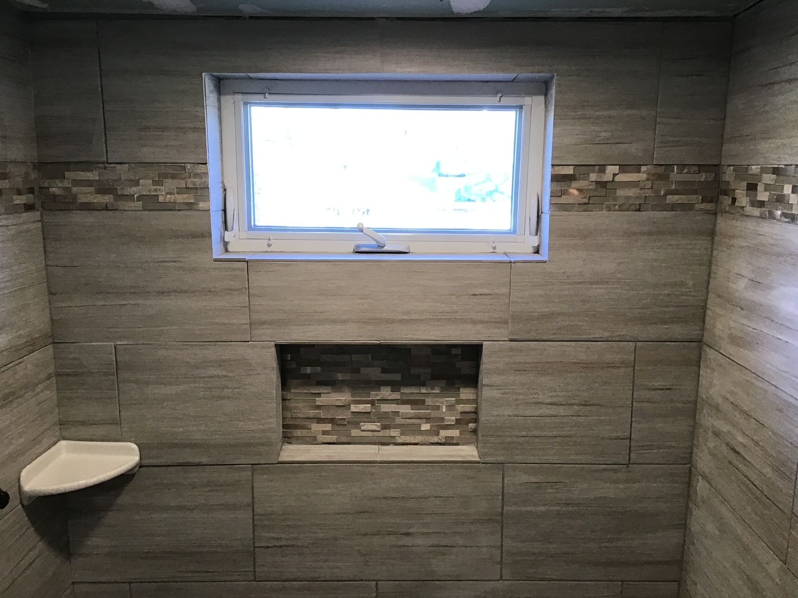 A bathroom with a window and a shelf in it
