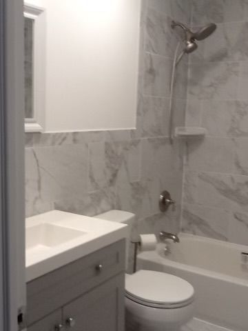 A bathroom with a toilet, sink, bathtub, and shower