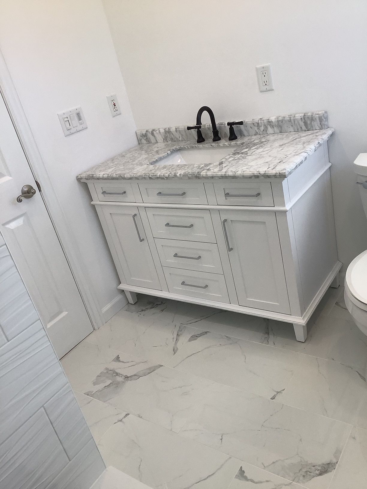 A bathroom with a white vanity, sink, and toilet