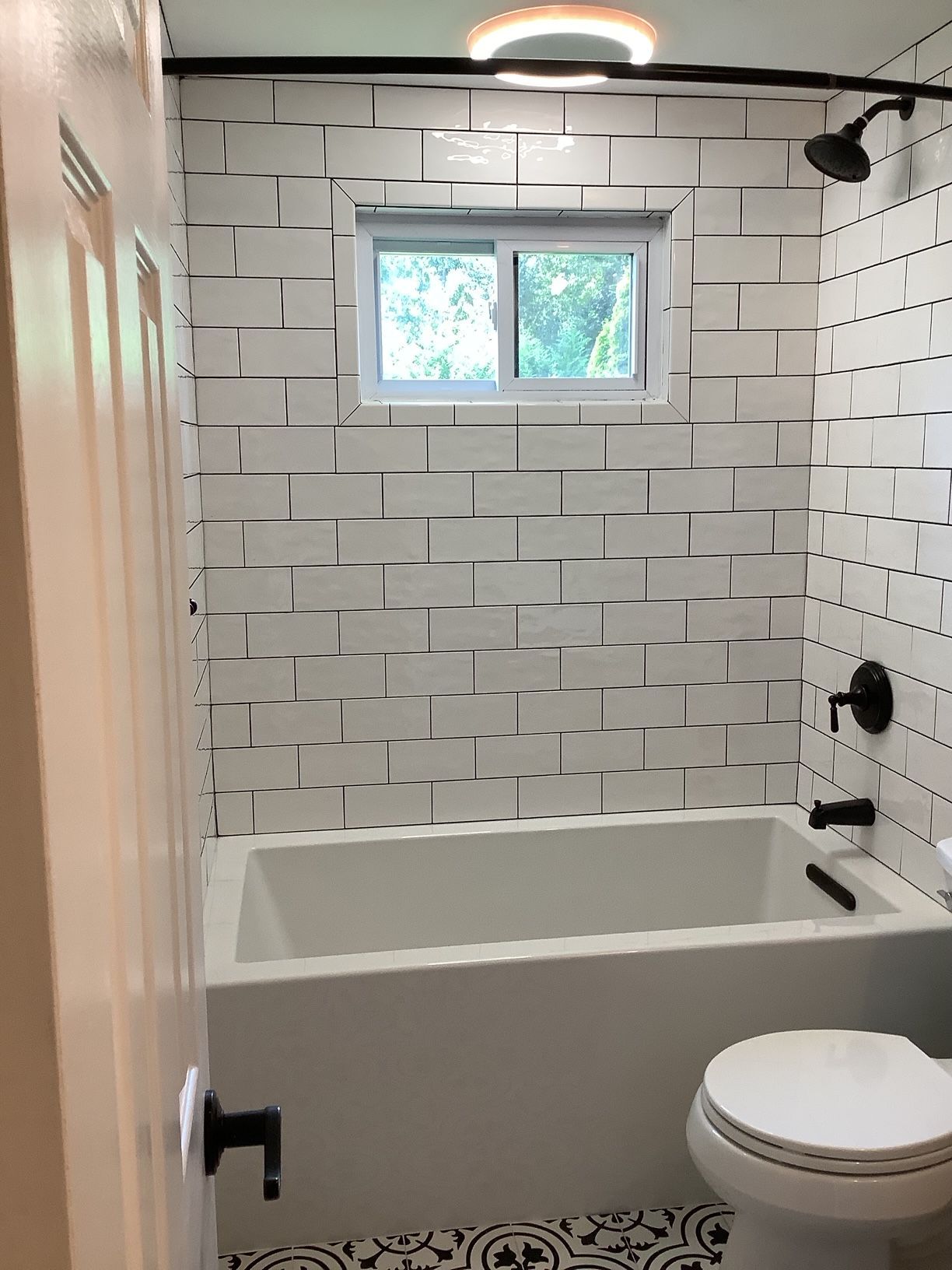 A bathroom with a tub, toilet, shower, and window