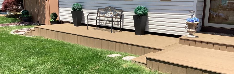 A porch with a bench and potted plants in front of a house