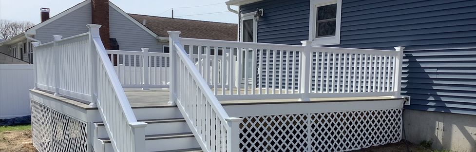 A blue house with a white deck and stairs leading up to it