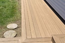 A wooden deck next to a lawn with stepping stones