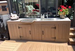 A kitchen with a sink and cabinets on a wooden deck