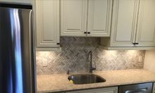 A kitchen with white cabinets, stainless steel appliances, a sink, and a refrigerator