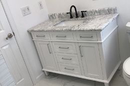 A bathroom with a white vanity, sink, and toilet