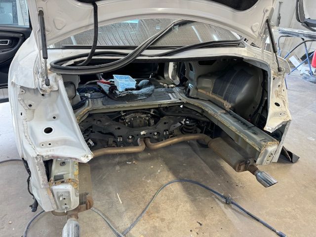 A white truck is parked in a garage with the hood open.