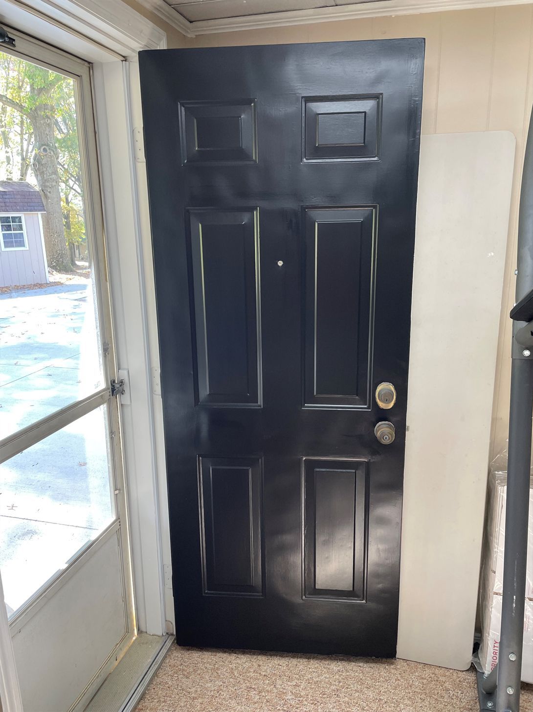 A black door is sitting in a room next to a window.