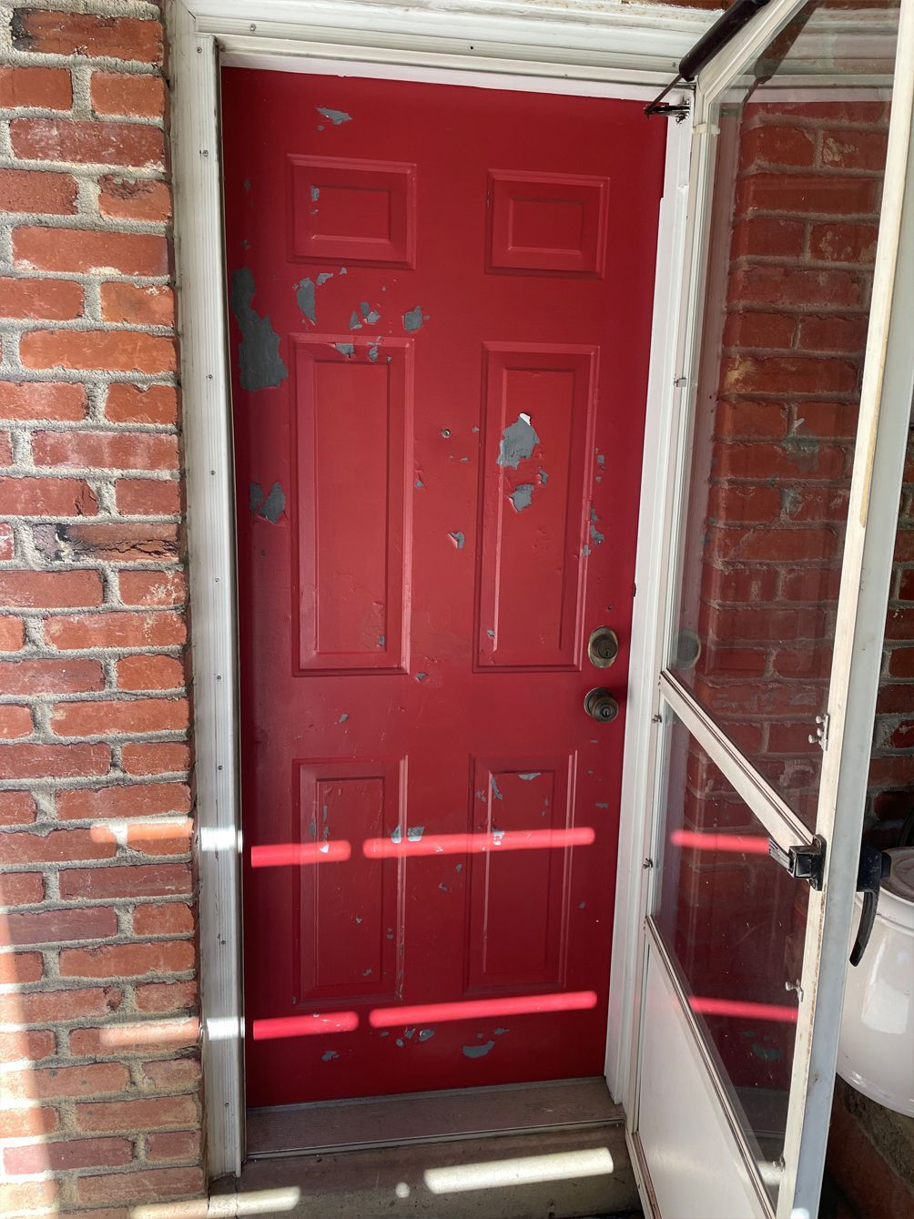 A red door with a brick wall behind it
