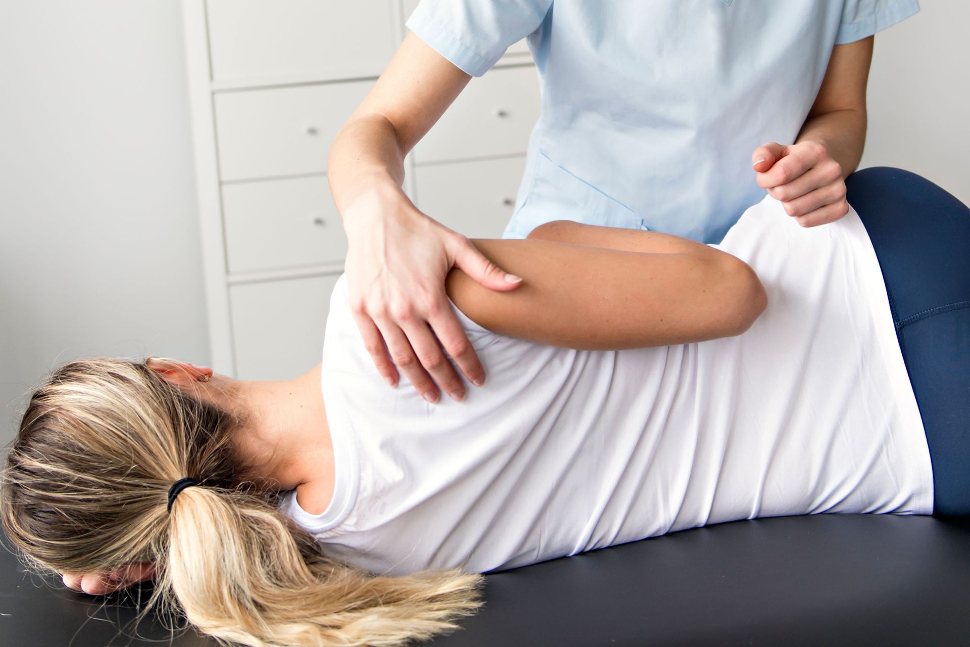 Person receiving back massage on a massage table. Hands of person performing the massage on patient's back.