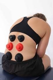 A woman is kneeling on a table with a bunch of red and black cups on her back.