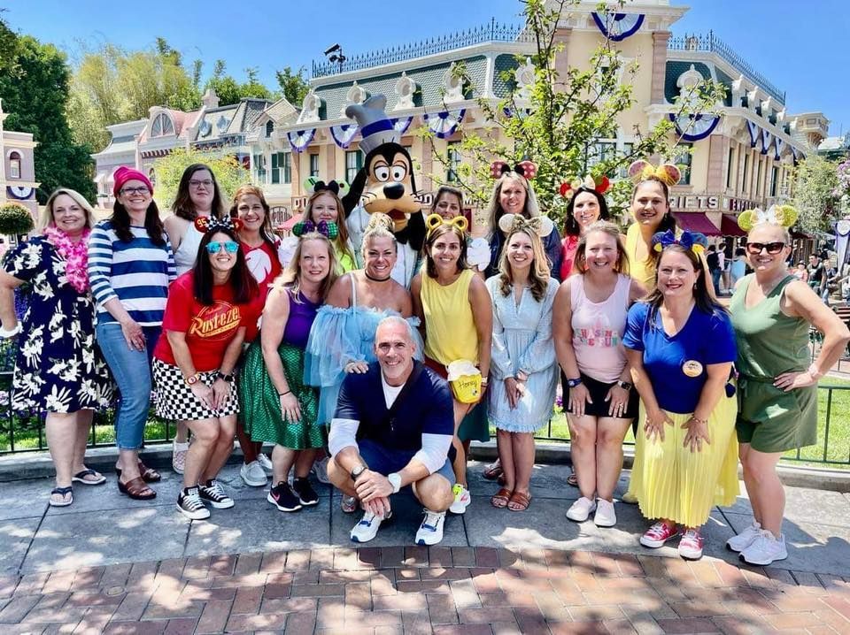 A group of people are posing for a picture with mickey mouse.