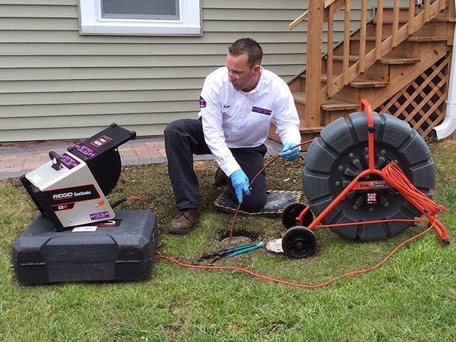 A man is fixing a sink pipe with a wrench