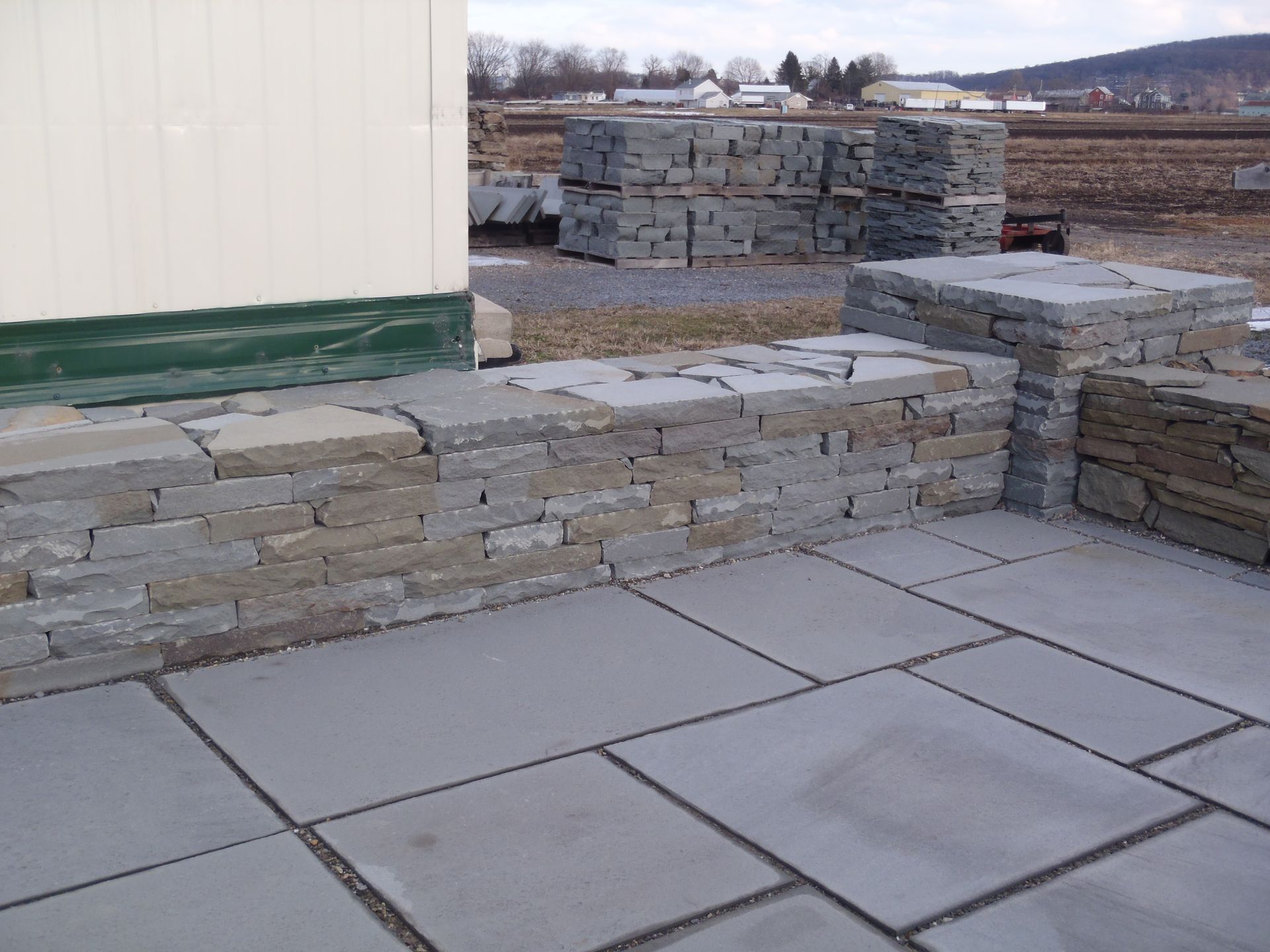 a patio with a stone wall in the background