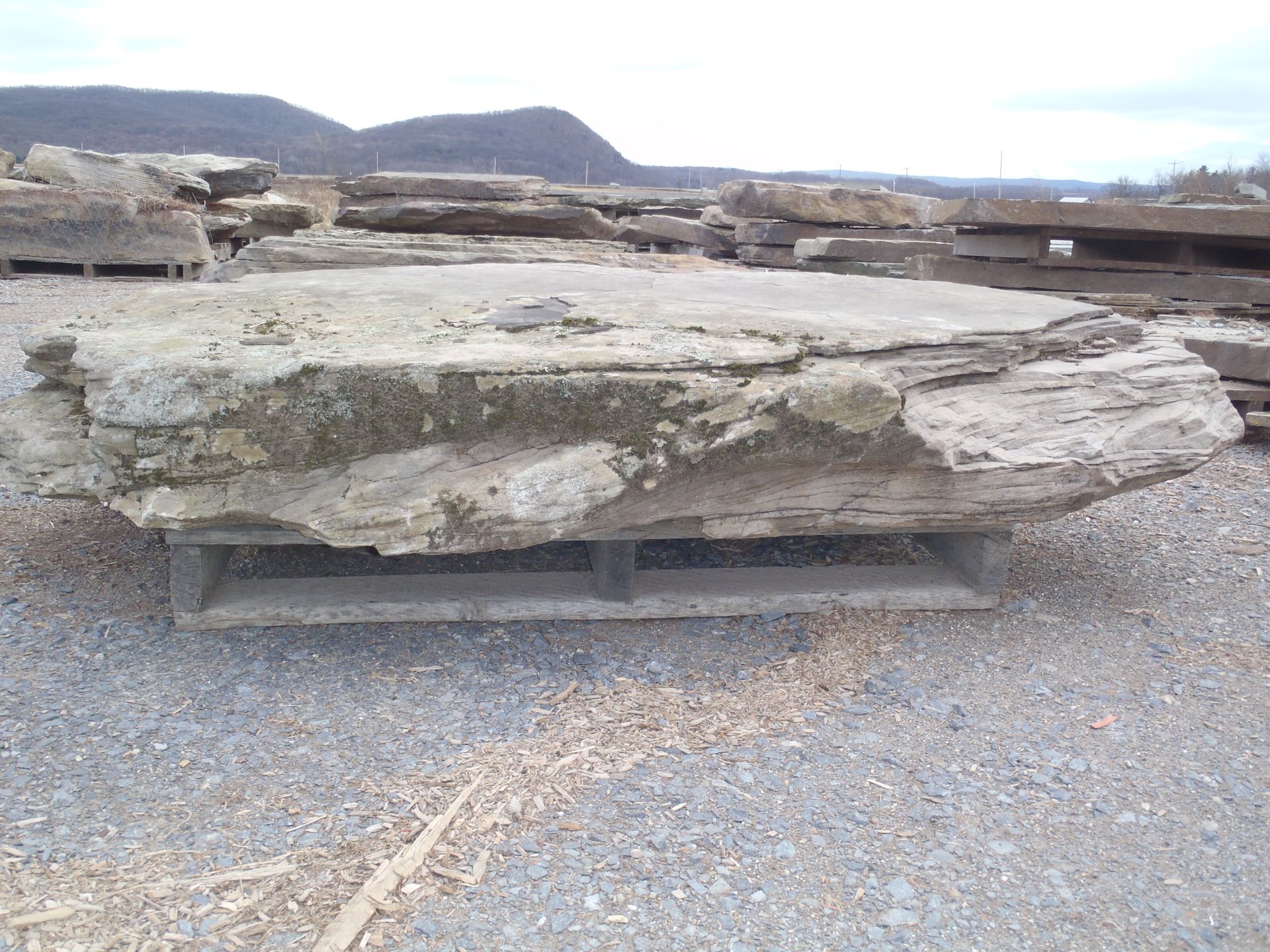 a large rock is sitting on a pallet in a gravel area
