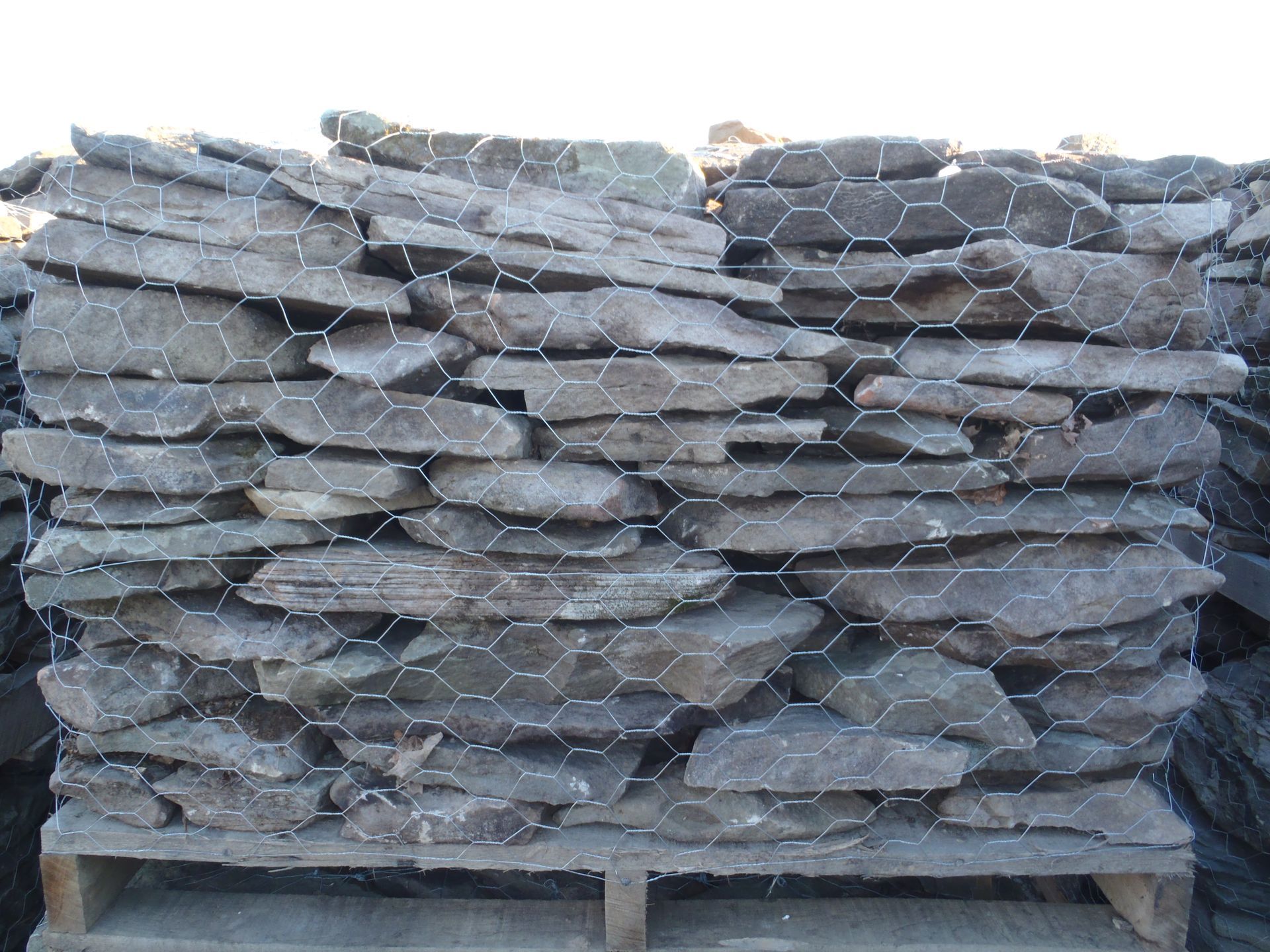 a pile of rocks sitting on top of a wooden pallet behind a chicken wire fence