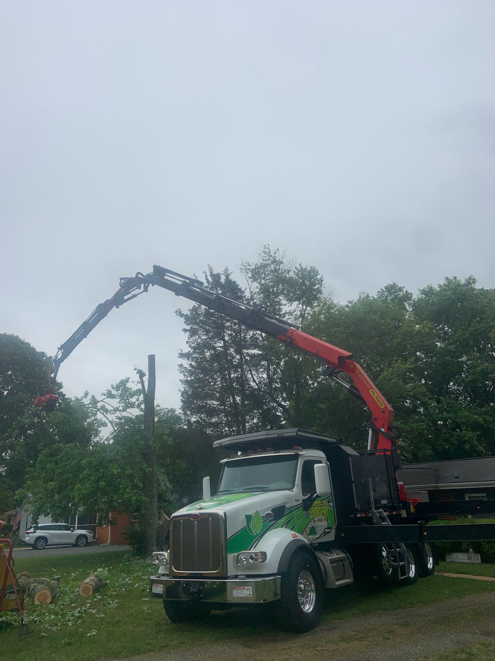 A truck with a crane attached to it is parked in a grassy area.