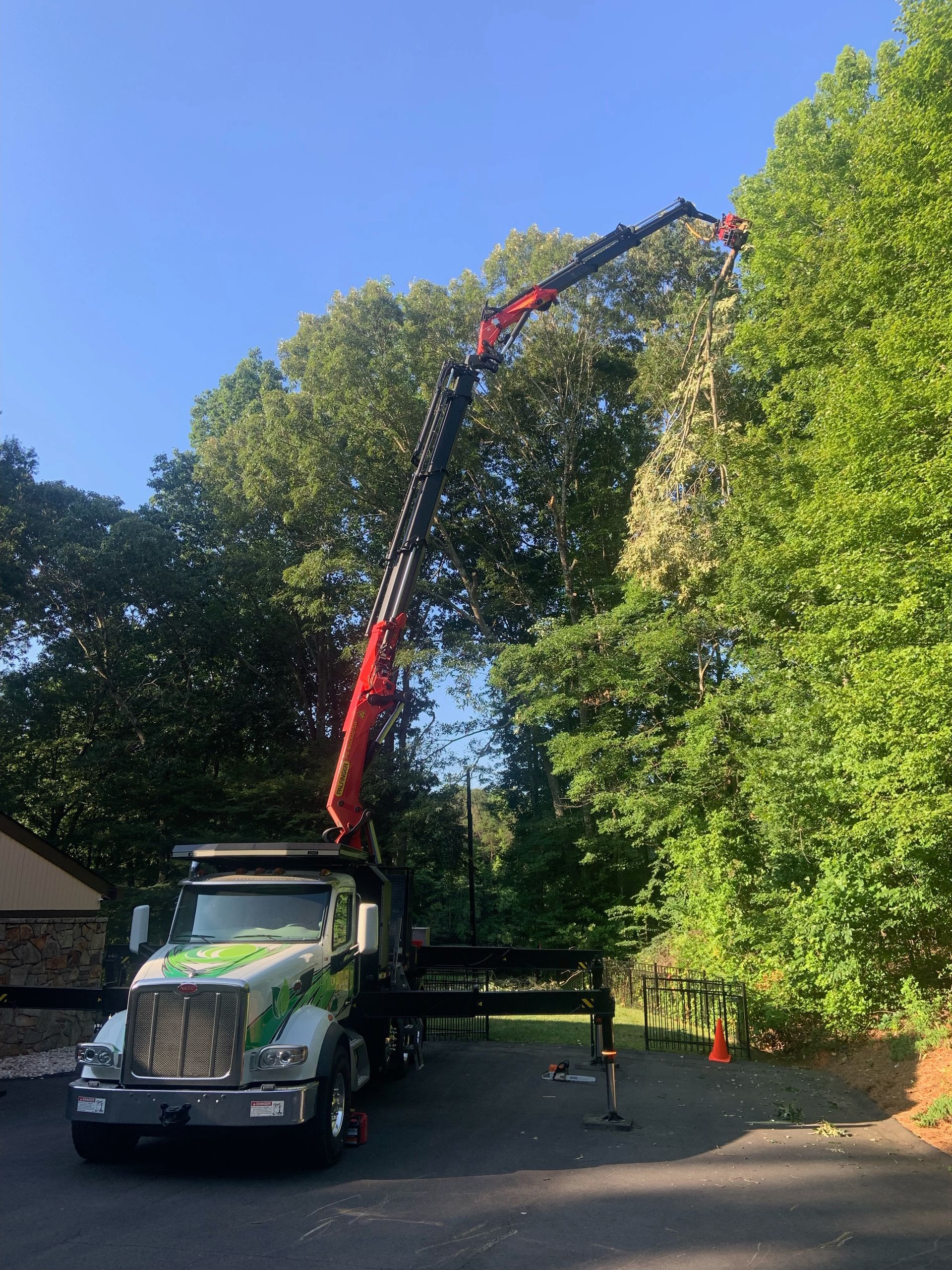 A truck with a crane attached to it is parked in a driveway.