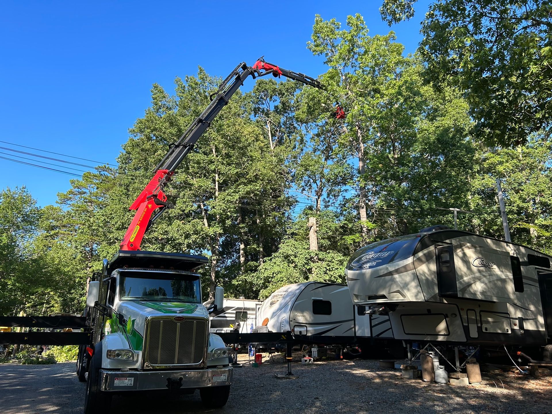 A truck with a crane attached to it is parked in front of a rv park.