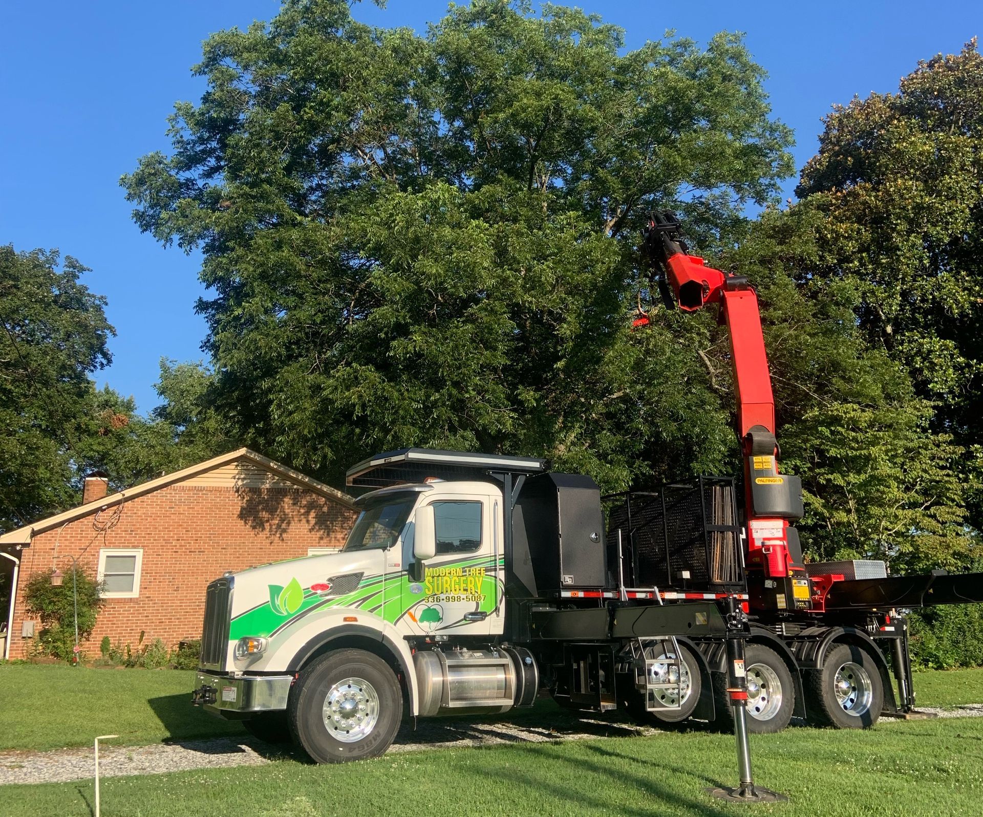A truck with a crane on the back is parked in front of a house.