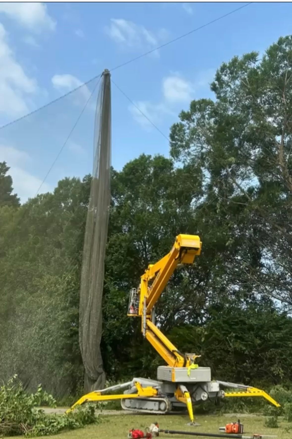 A yellow crane is working on a golf course.