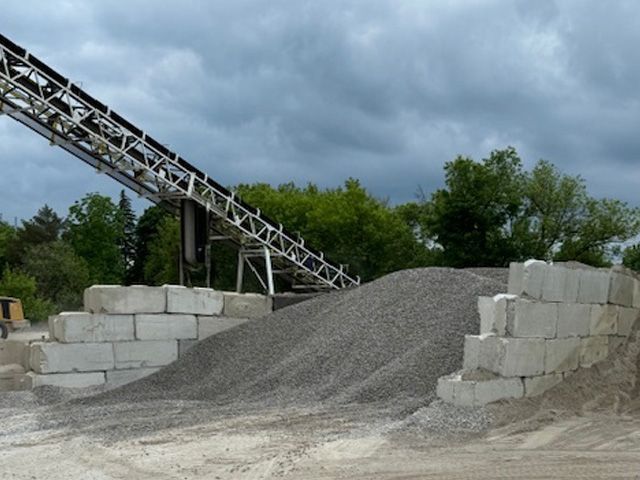 A conveyor belt is going over a pile of gravel
