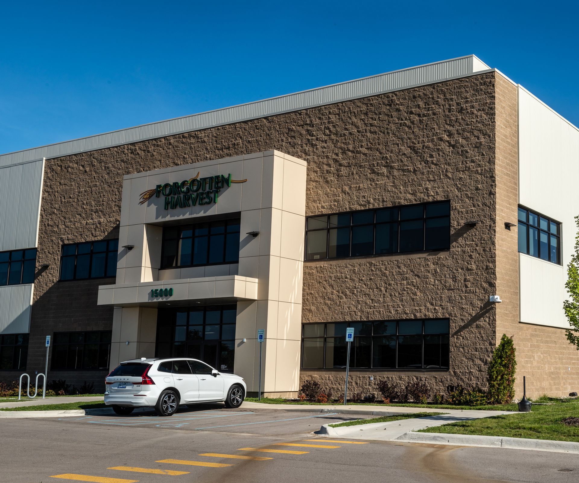 A white suv is parked in front of a large building that says agricultural markets