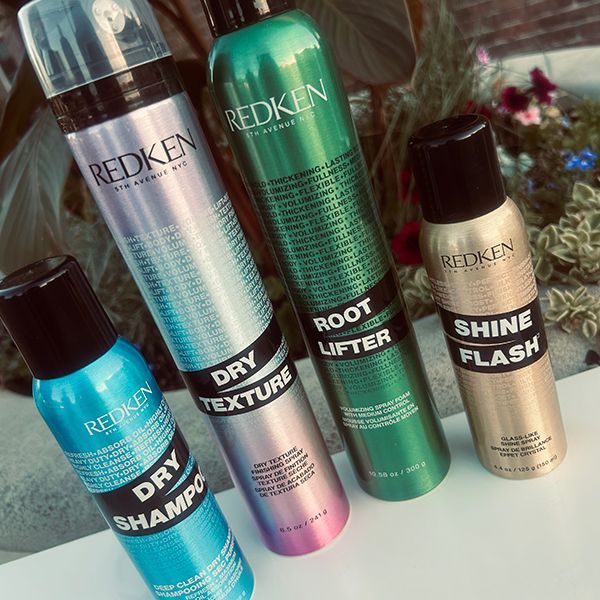 Four Redken hair styling product cans: dry shampoo, dry texture, root lifter, and shine flash.