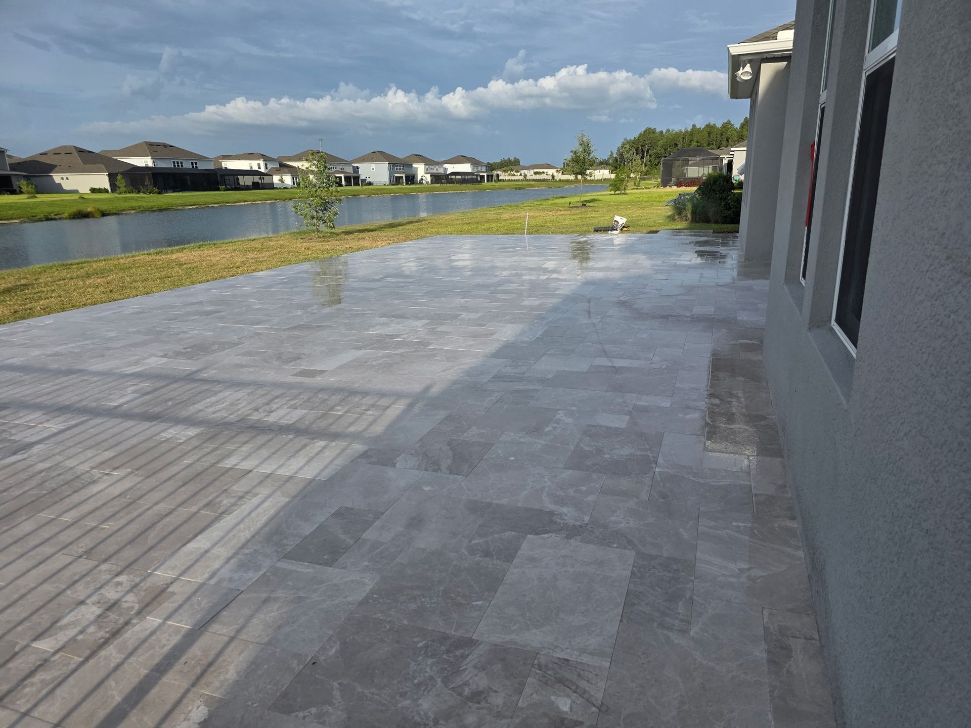 Backyard patio with gray pavers beside a house, overlooking a river