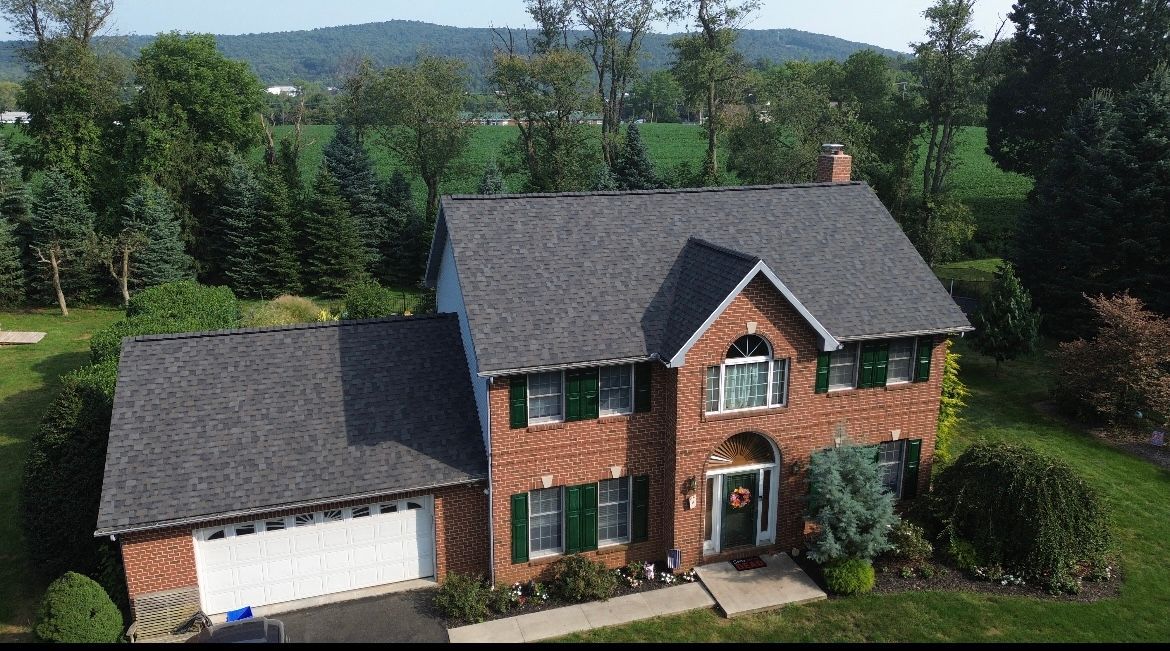 An aerial view of a large brick house with a gray roof