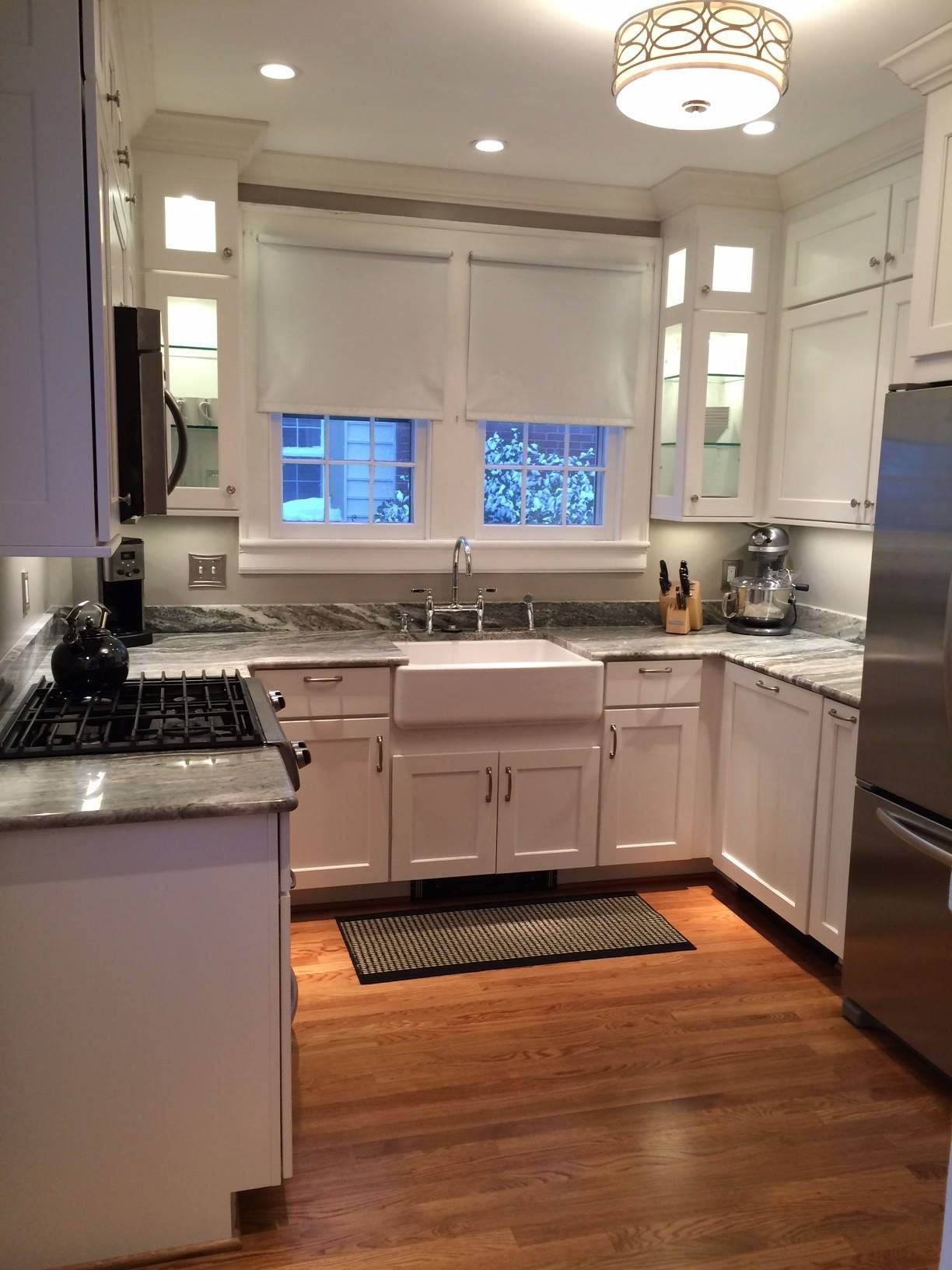 White kitchen with granite countertops, stainless steel appliances, and hardwood floors.