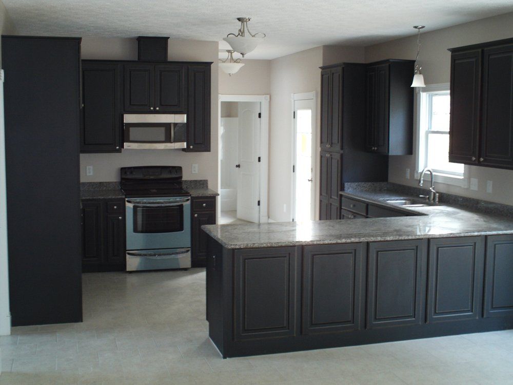 Dark kitchen with granite countertops, stainless steel appliances, and black cabinets.