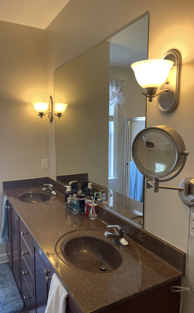Bathroom with double sinks, a large mirror, and two sconces.