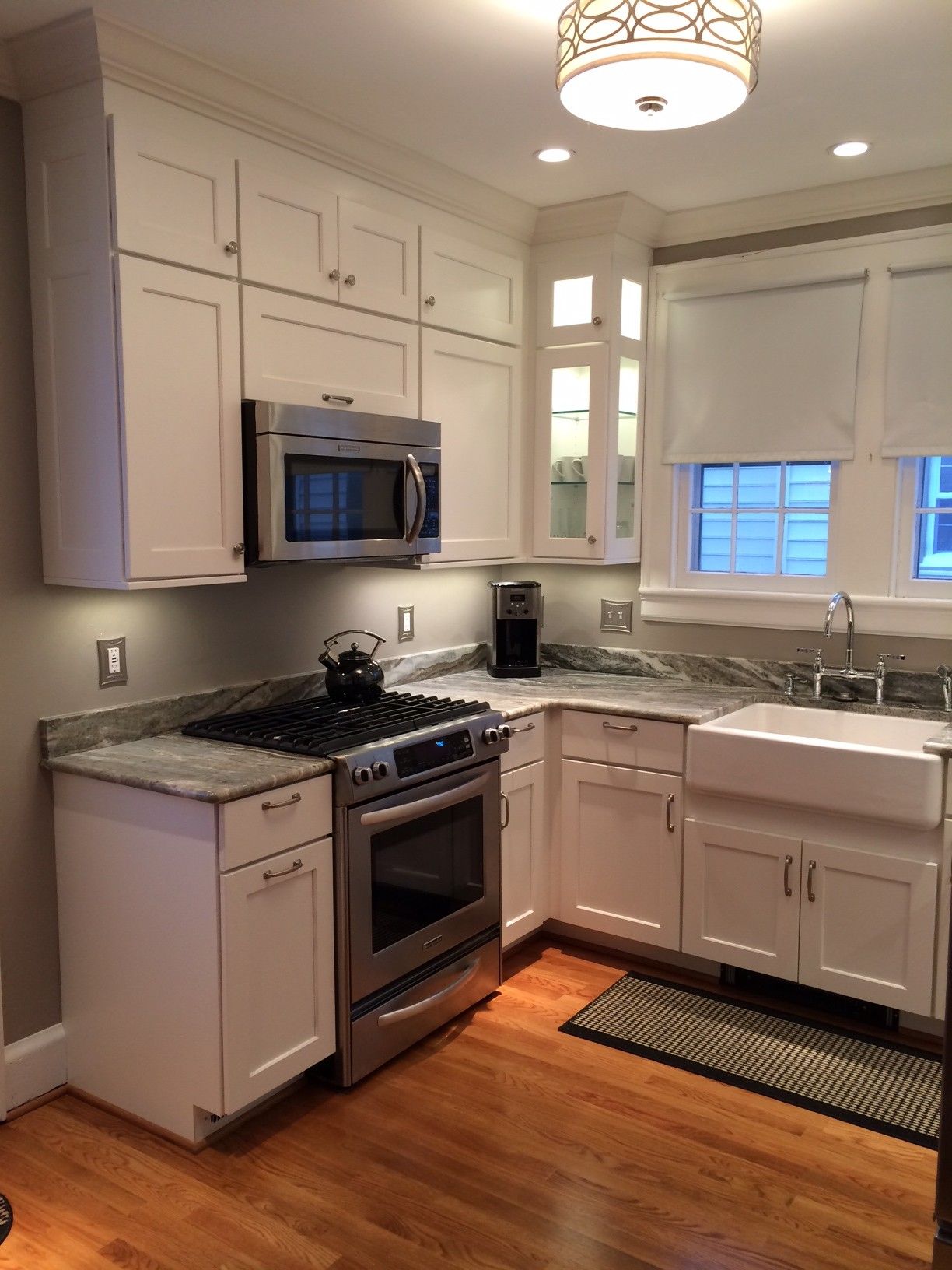 White kitchen with stainless steel appliances, granite countertops, and a farmhouse sink.