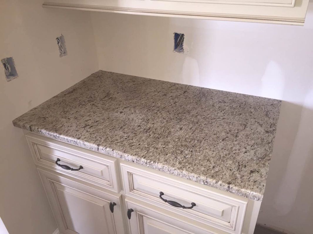 A kitchen counter with a granite counter top and white cabinets.