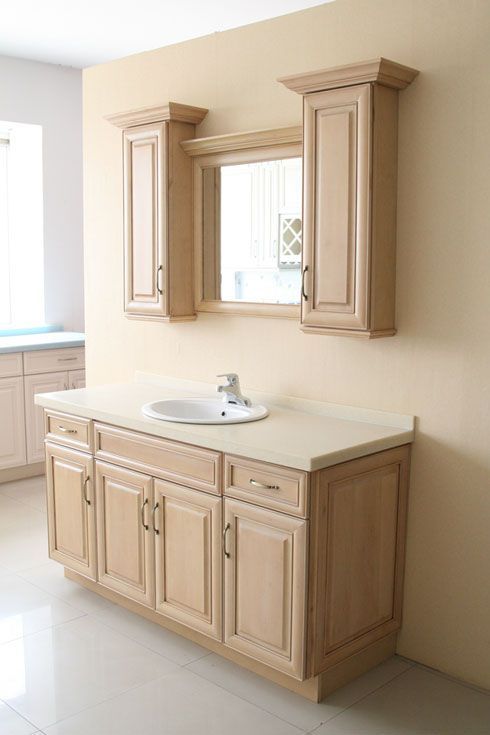 A bathroom with a sink , cabinets , and a mirror.