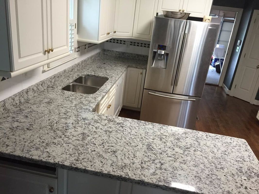 A kitchen with granite counter tops and a stainless steel refrigerator.