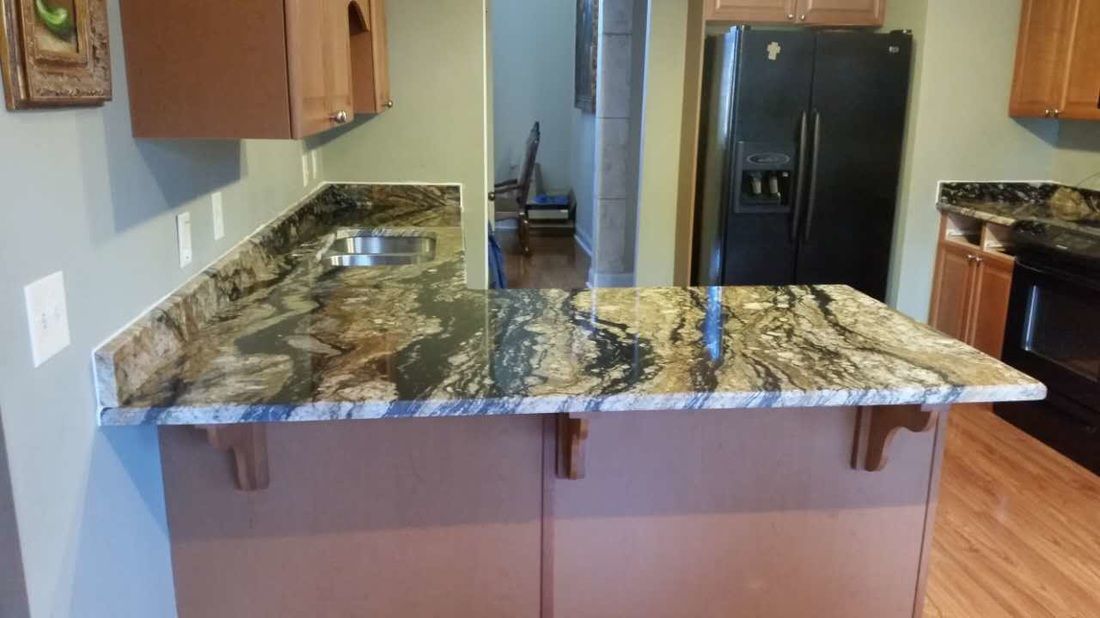 A kitchen with a granite counter top and a black refrigerator.