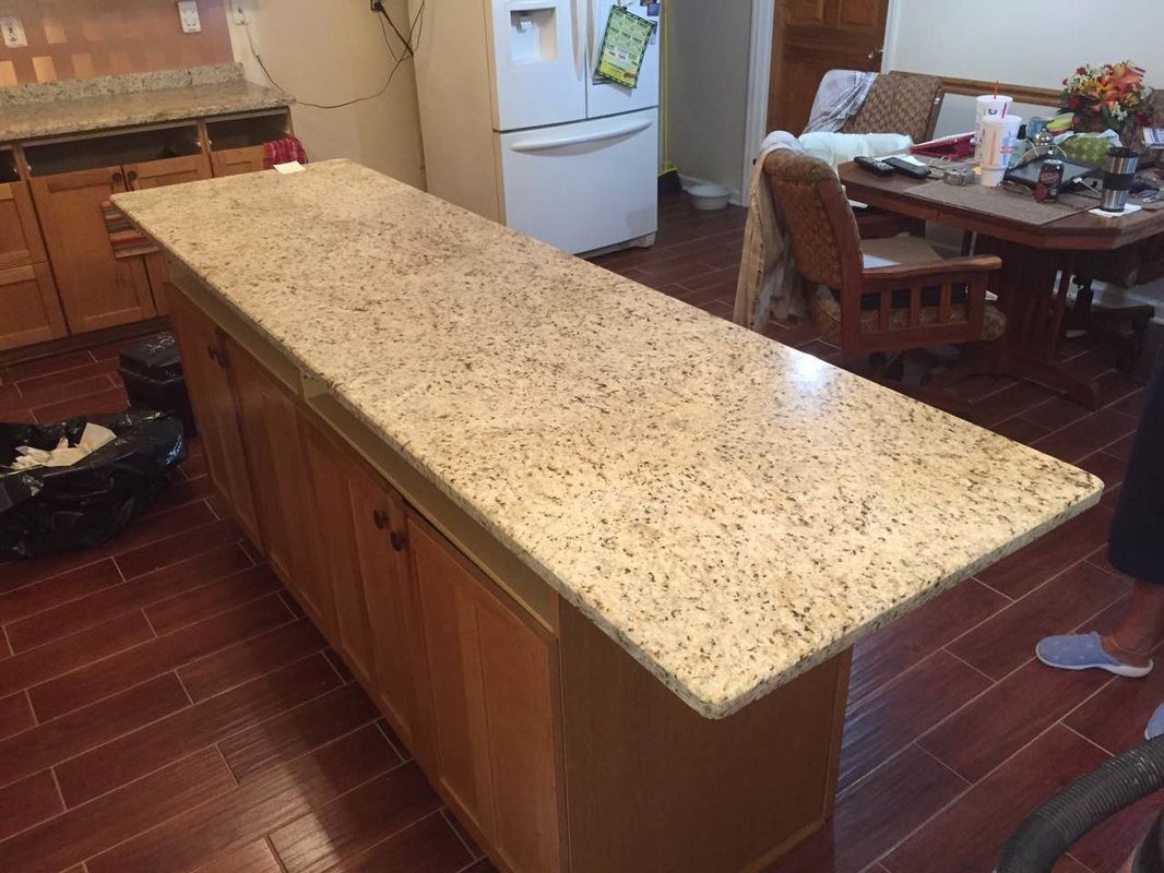 A kitchen with a large granite counter top and a refrigerator.