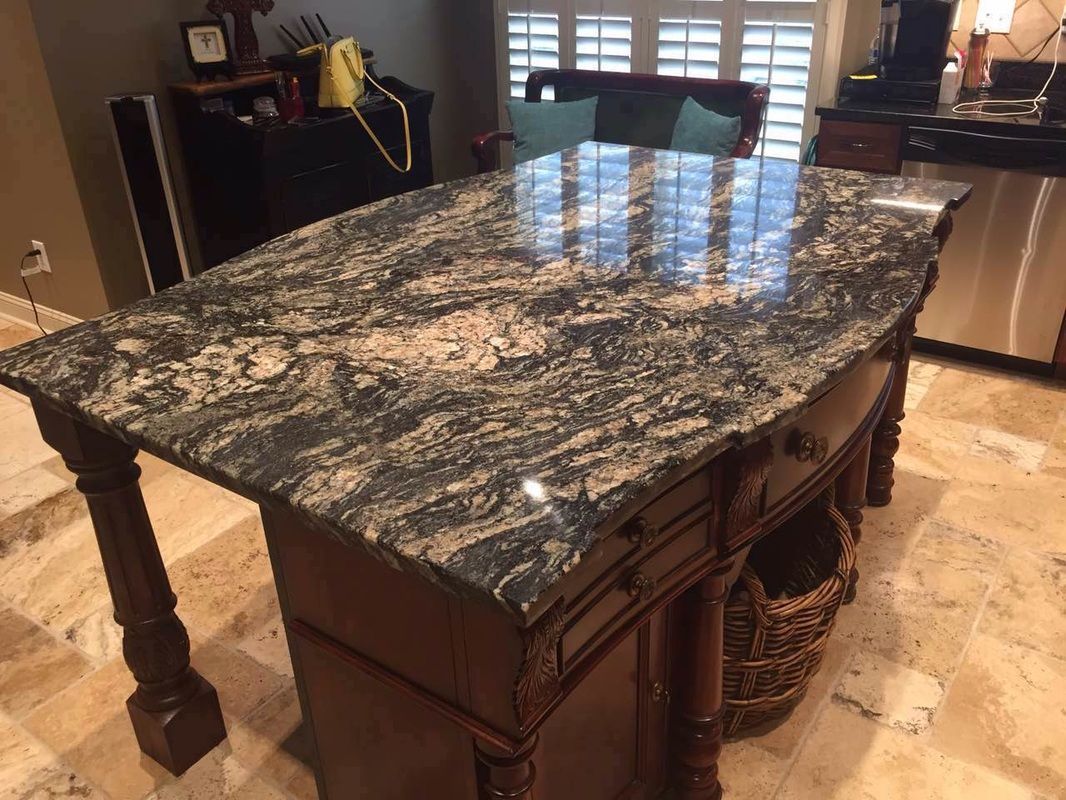 A kitchen island with a large granite counter top.