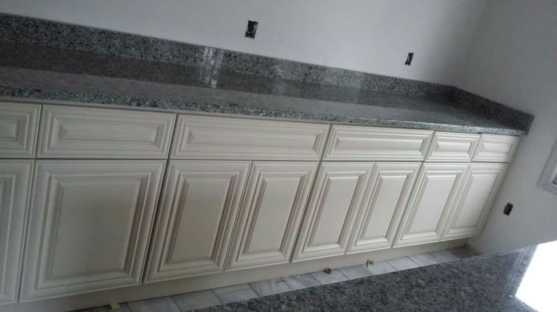 A kitchen with white cabinets and granite counter tops.