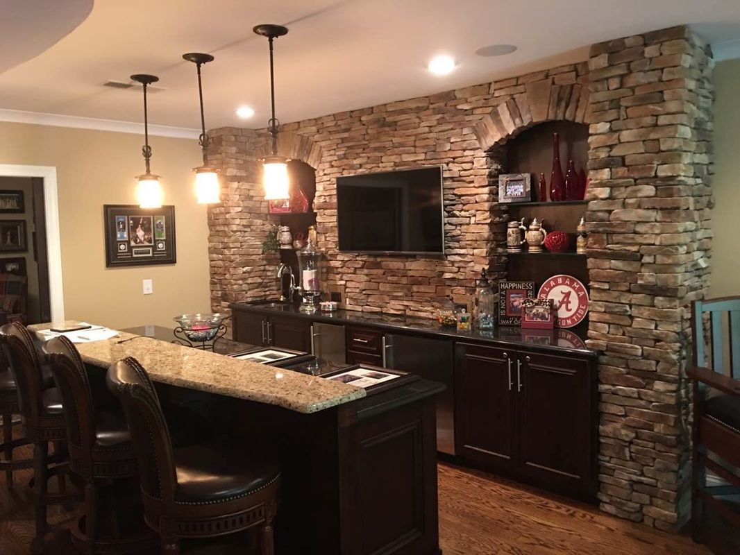 A kitchen with a bar and a stone wall
